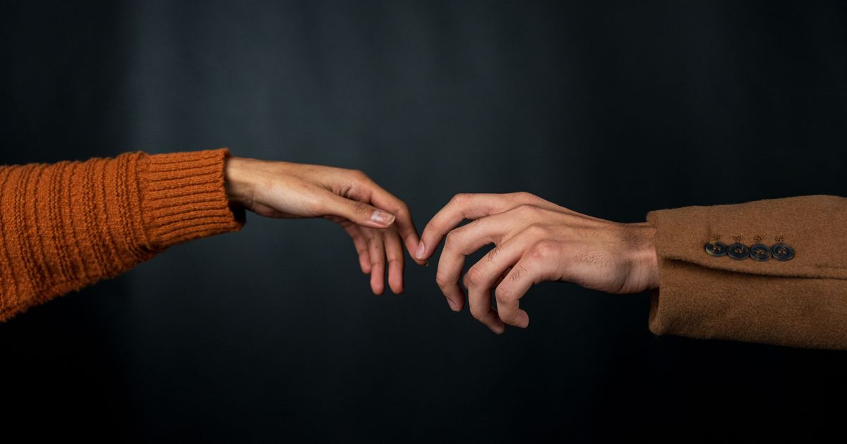 Two hands reaching toward each other, representing authentic brand storytelling and human connection
